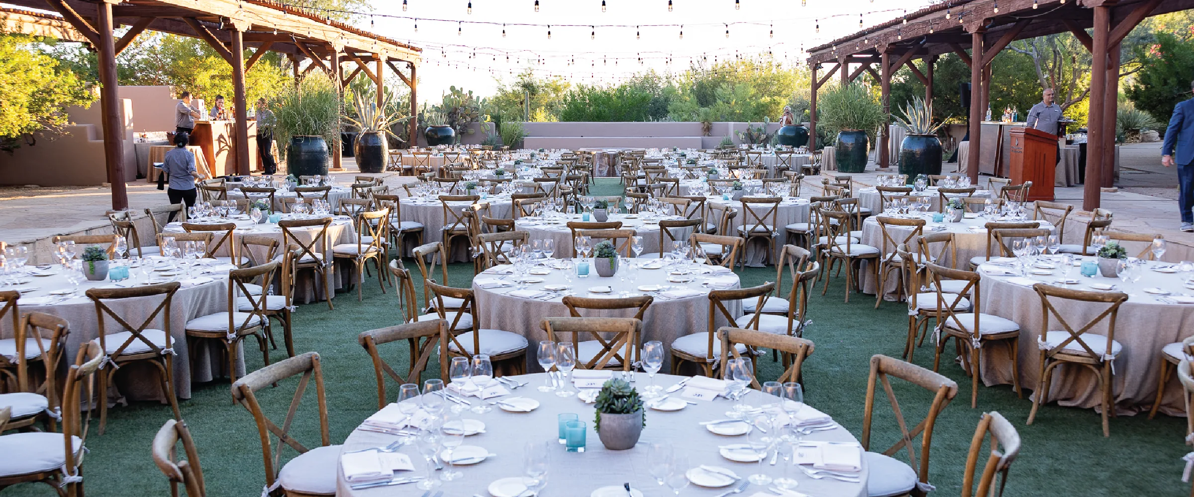 Outdoor summit dinner setup with round tables under string lights