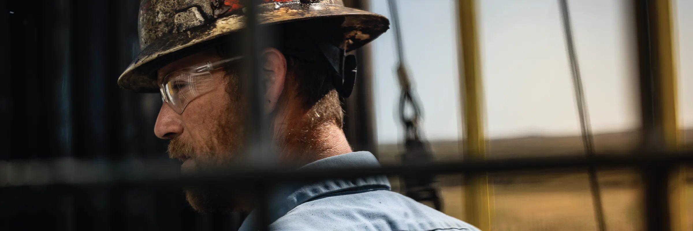Portrait of a crew member in a hard hat seen through the rig structure