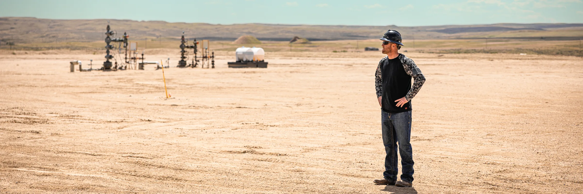 Crew member overlooking wellheads on the open plain