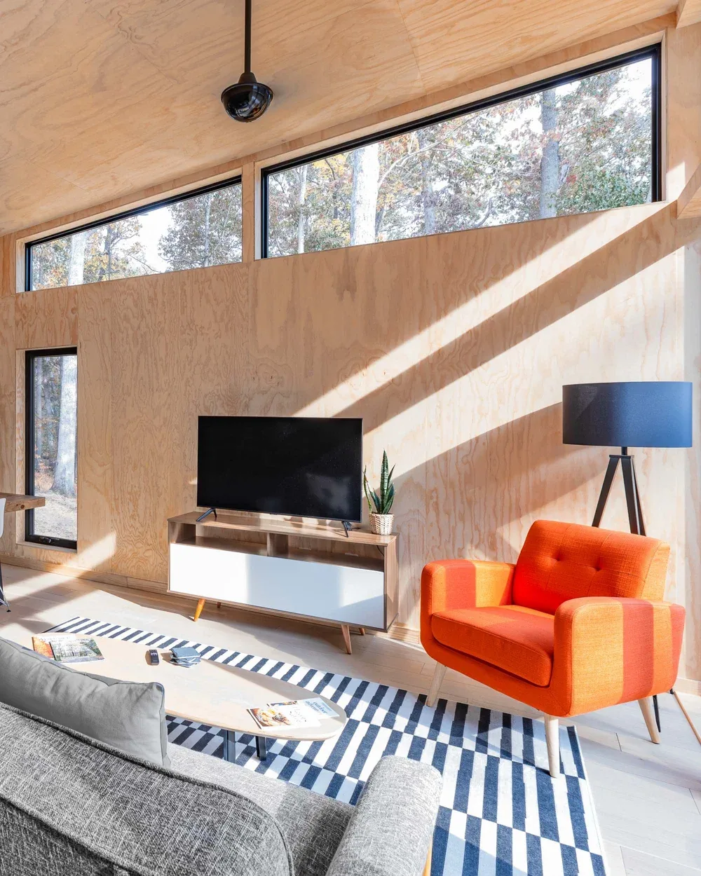 PlaHaus modern living room with plywood interior and orange armchair