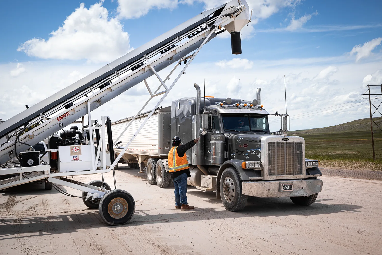 Crew loading a conveyor truck on a high-plains jobsite