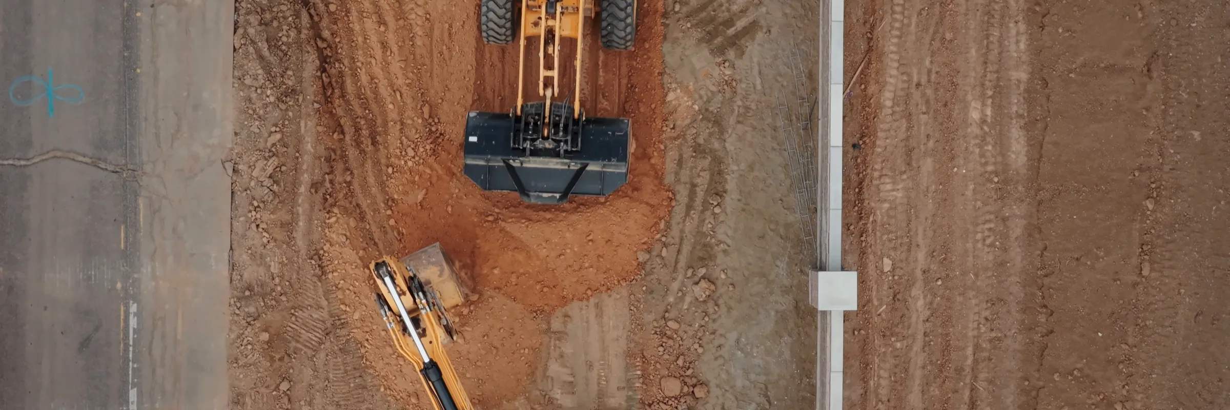 Drone view straight down on an excavator digging a utility trench